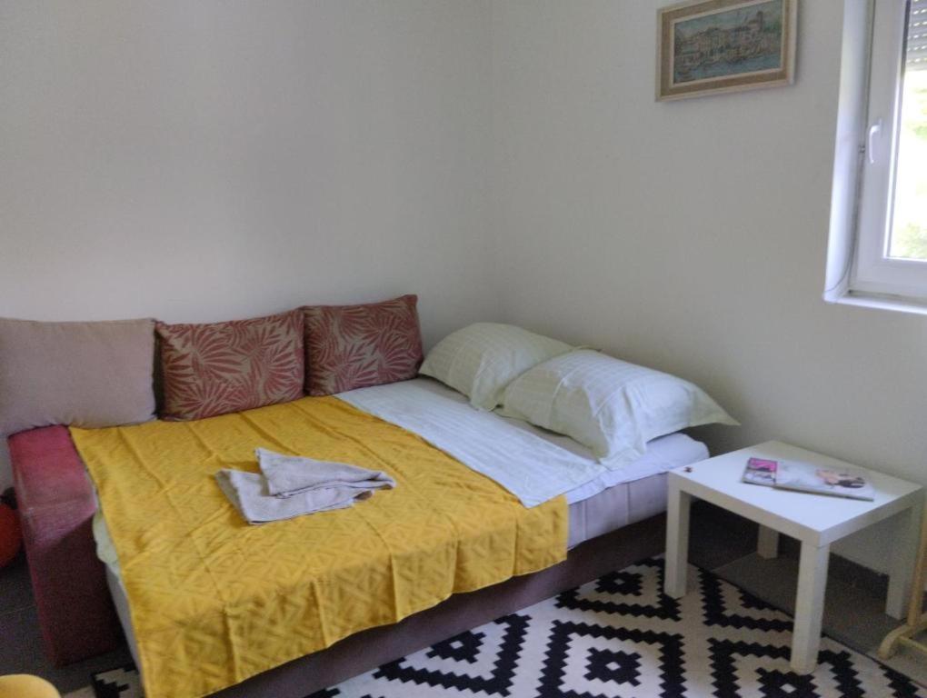 a small bed in a room with a yellow blanket at Summer House in Belgrade