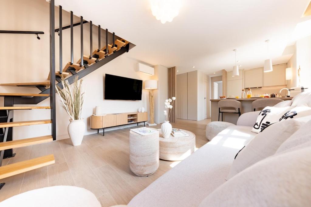 a living room with a white couch and a staircase at Élégant duplex 8 pers clim et suite parentale in Vallauris