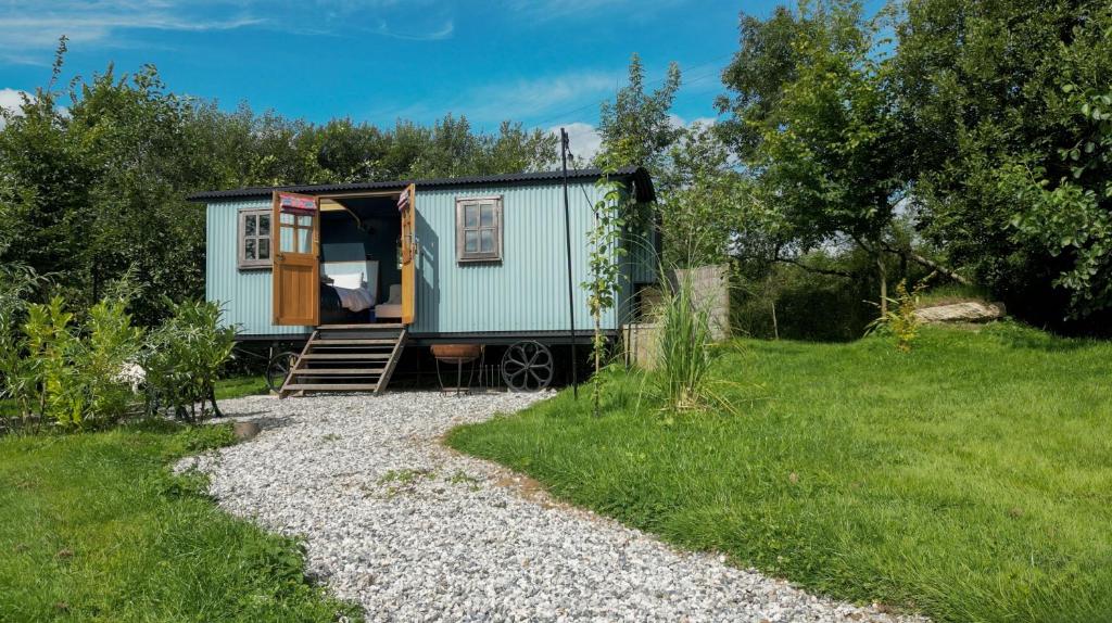 a green tiny house sitting in a yard at Da Vinci's Den in North Tawton