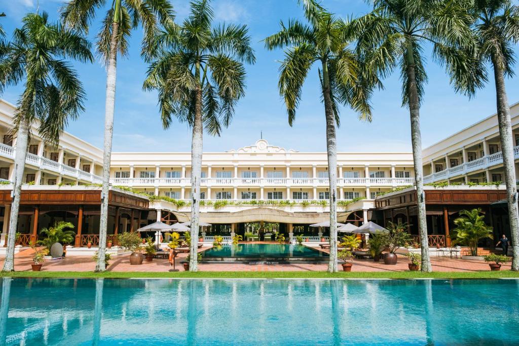 an exterior view of a hotel with palm trees at Victoria Can Tho Resort in Can Tho