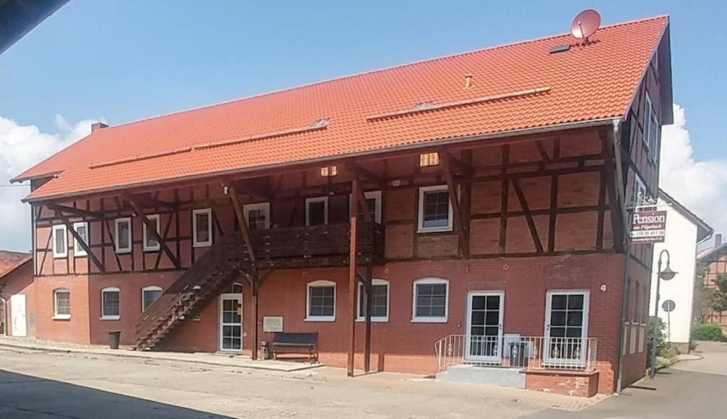 a large brown building with a red roof at Pension Am Pilgerbach in Baunatal