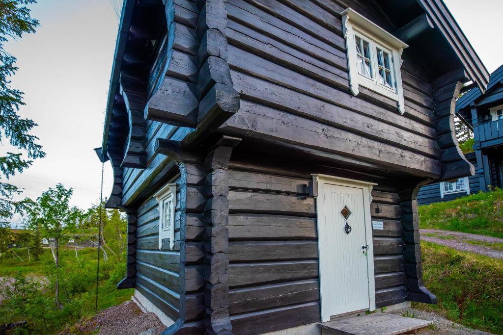 ein kleines Haus mit einer weißen Tür und Fenstern in der Unterkunft Trysilfjellet Nord 901 stabur in Trysil