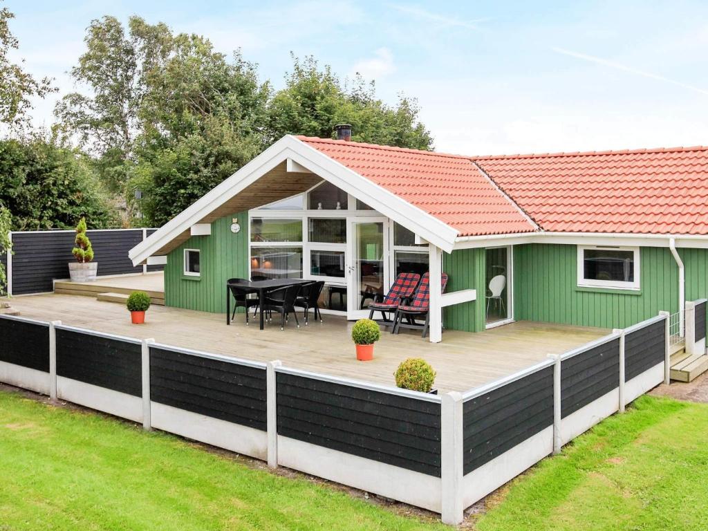 a green house with a large wooden deck at Seaside Bliss with Spa - By Traum Ferienwohnungen in Otterup