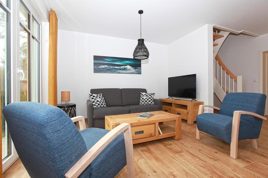 a living room with a couch and chairs and a tv at Haus Eichkater in Dierhagen