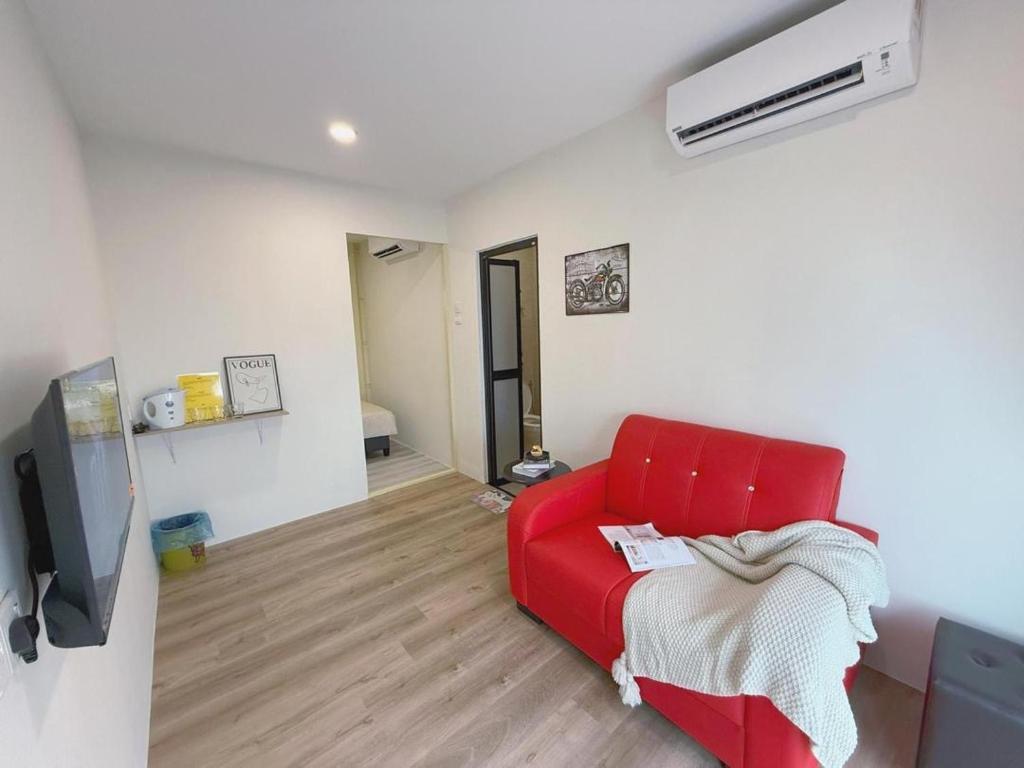 a living room with a red couch and a tv at 69 Comfortainer Homestay in Taiping