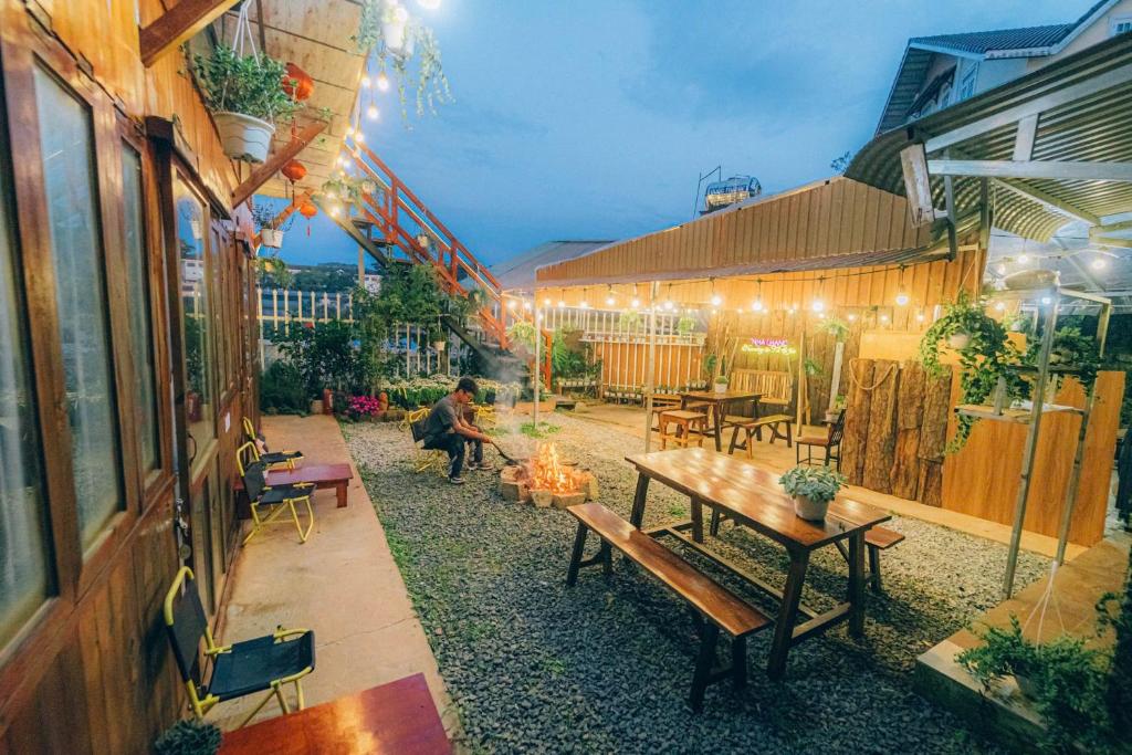 an outdoor patio with tables and benches and lights at D Home Retreat Hùng Vương Đà Lạt in Khu Chi Lăng