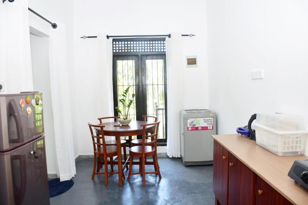 Una cocina con mesa y sillas y un refrigerador. en Sureka Home Stay, en Habaraduwa Central