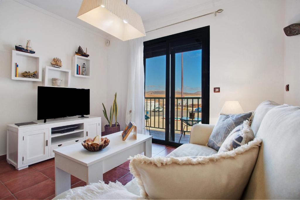 Una sala de estar con un sofá y un televisor. en Casa Ferry, en Puerto de las Lajas