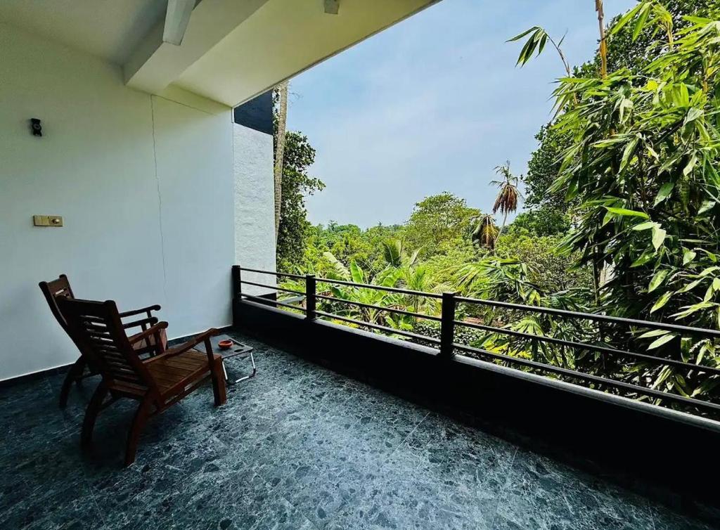 a balcony with a chair and a view of the forest at Villa Green View in Hikkaduwa