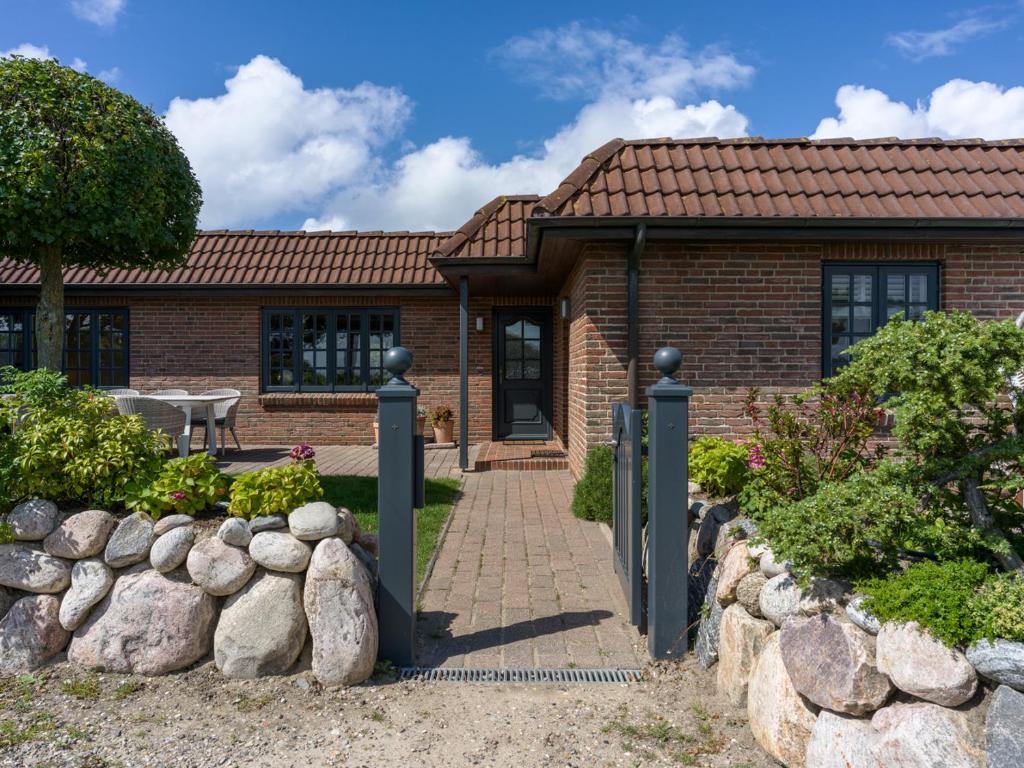 una casa de ladrillo con un camino que conduce a la puerta principal en Beach Bungalow Sylt 2, en Dikjendeel