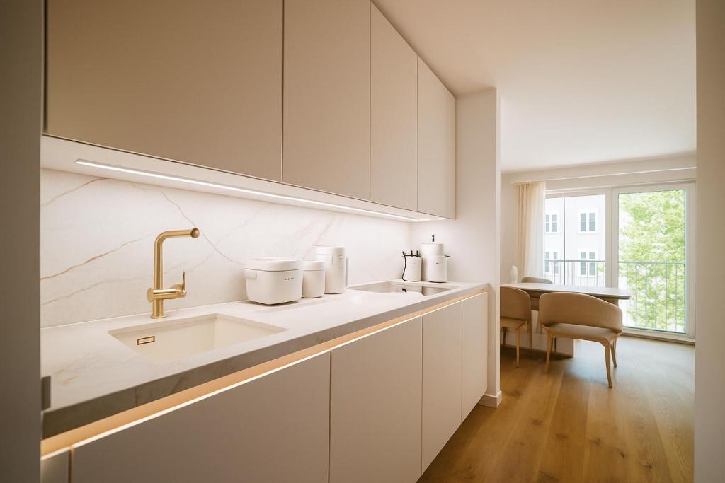 a white kitchen with a sink and a table at Lindgold in Munich