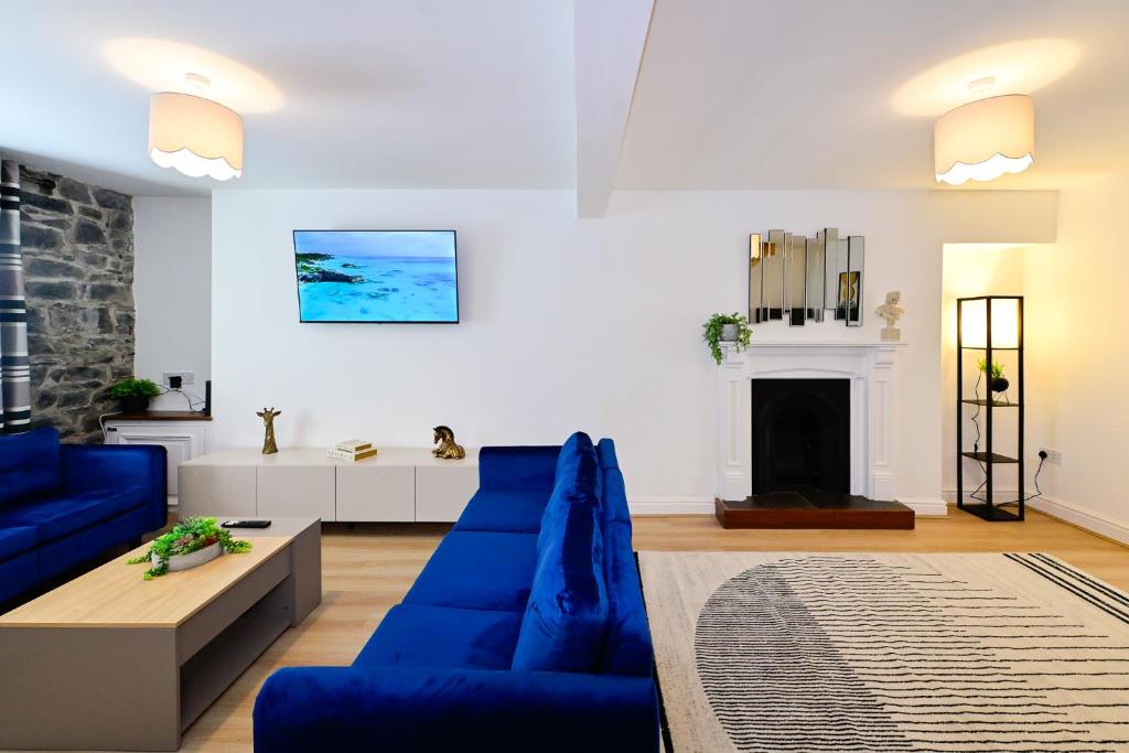a living room with blue couches and a fireplace at Cosy Mumbles Escape Fun & Relax in The Mumbles