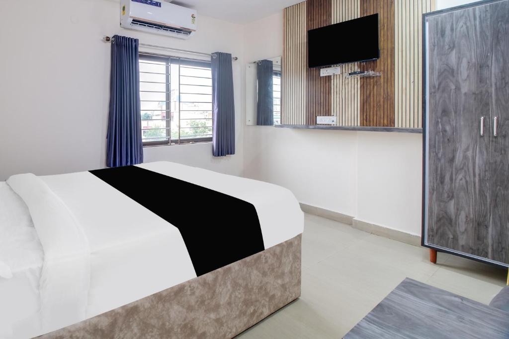 a bedroom with a bed and a flat screen tv at Hotel O Sai Capital in Vijayawada
