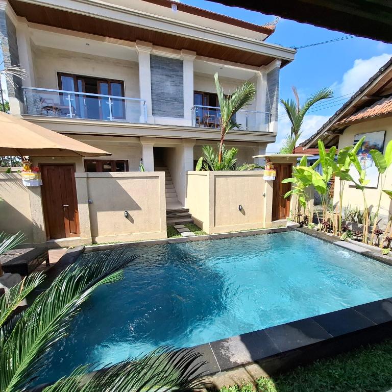 a swimming pool in front of a house at DJumah House in Ubud