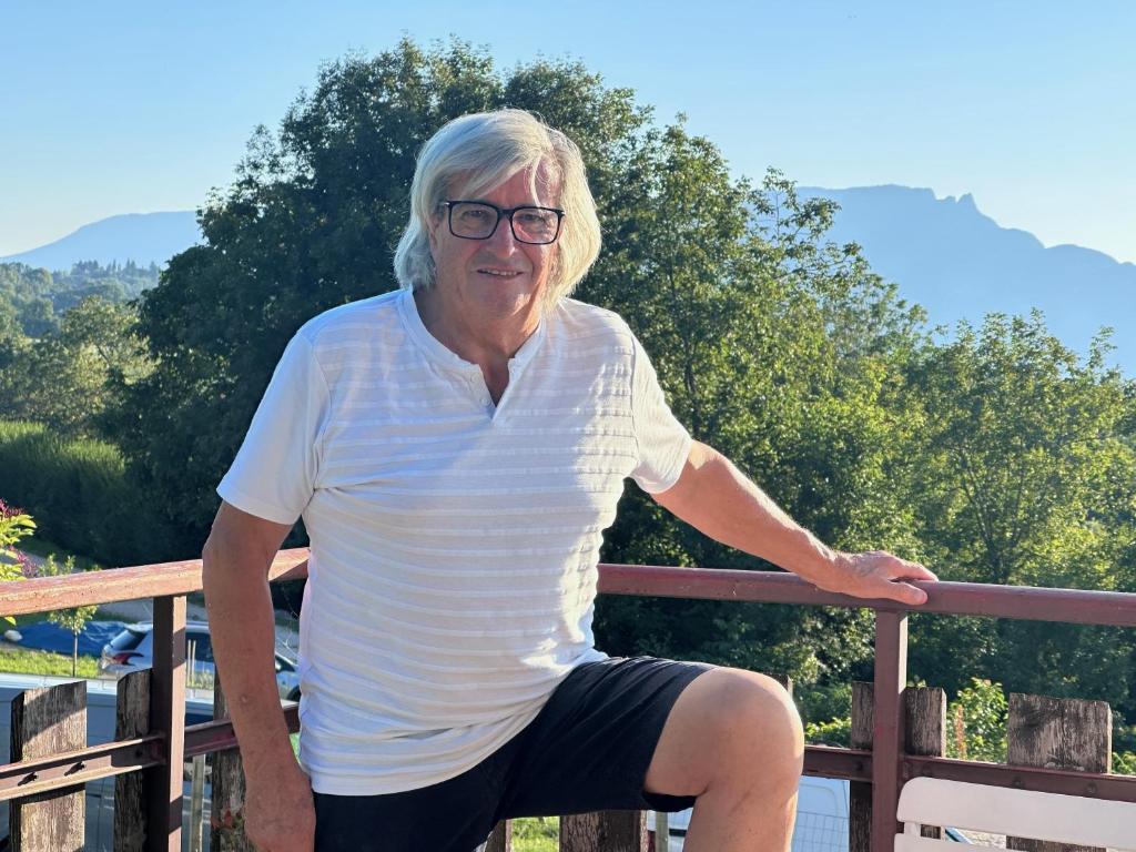 an older man is sitting on a fence at Le chalet st hubert in Montcel