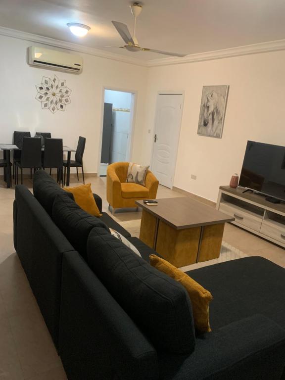 a living room with a black couch and a tv at Cozy comfortable One bedroom close to Airport in Accra