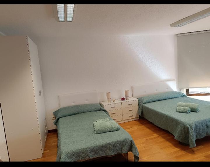 2 letti in una camera bianca con coperte verdi di Habitación para descansar en pleno centro ad Alicante