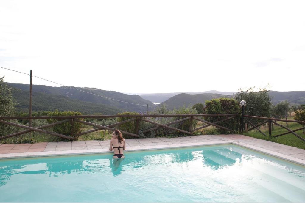 a woman is standing in a swimming pool at Agriturismo Podere Acqualoreto in Acqualoreto