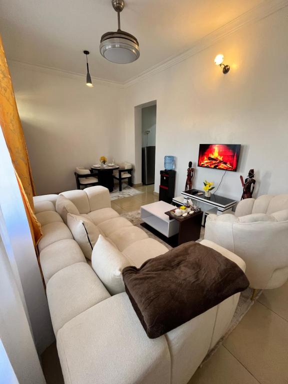 By the Coastals في مومباسا: غرفة معيشة مع أريكة بيضاء وتلفزيون
