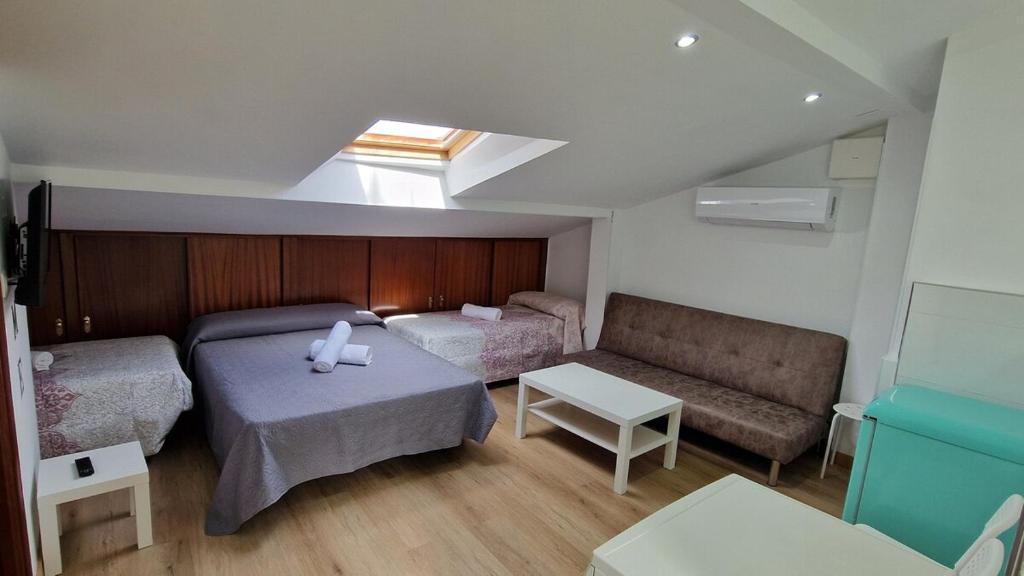 Habitación pequeña con 2 camas y sofá en Serranos Salamanca Centro, en Salamanca