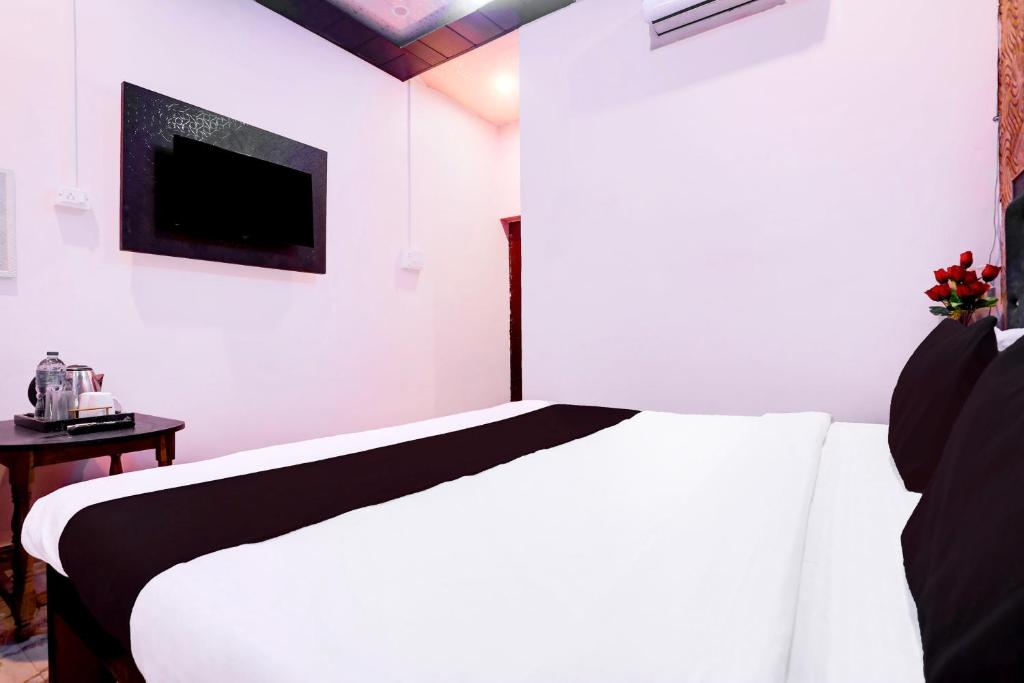 Un dormitorio con una cama blanca y un televisor. en Hotel O S B Guest house, en Varanasi