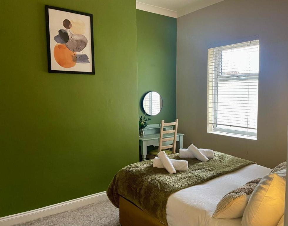 - une chambre avec des murs verts et un lit avec un bureau dans l'établissement 3-Bed Home Close to City Centre, Stadium & Baltic, à Newcastle upon Tyne
