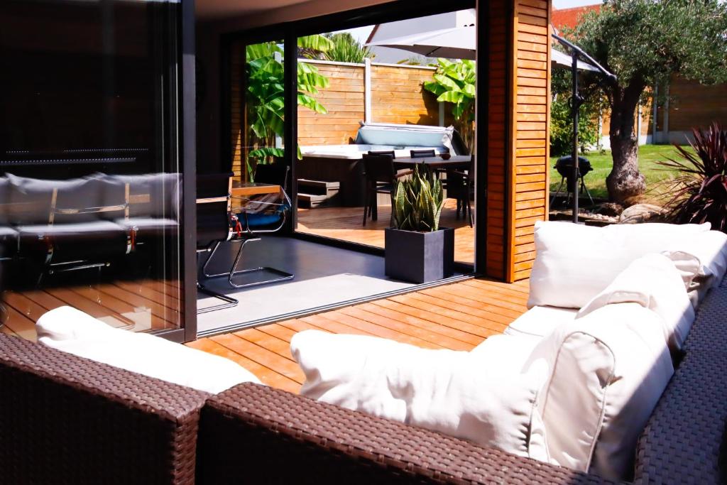 a patio with white couches on a wooden deck at Grange rénovée- 3 chambres spa in Basly
