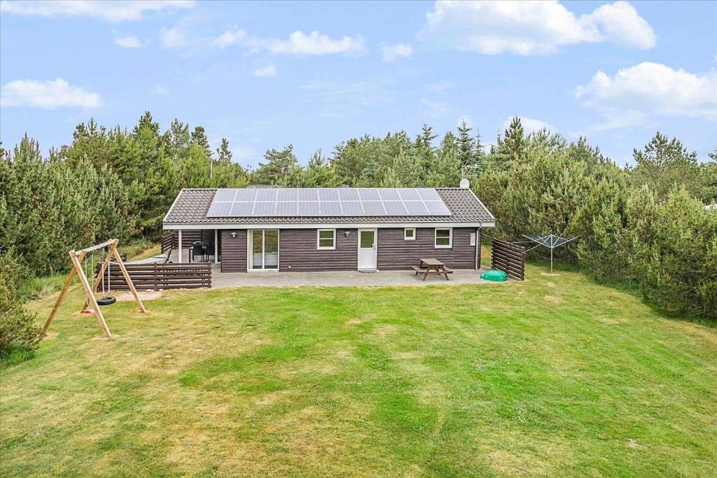 uma pequena casa com um parque infantil num quintal em JB699-Fjerritslev-Revlingestien-43 em Torup Strand