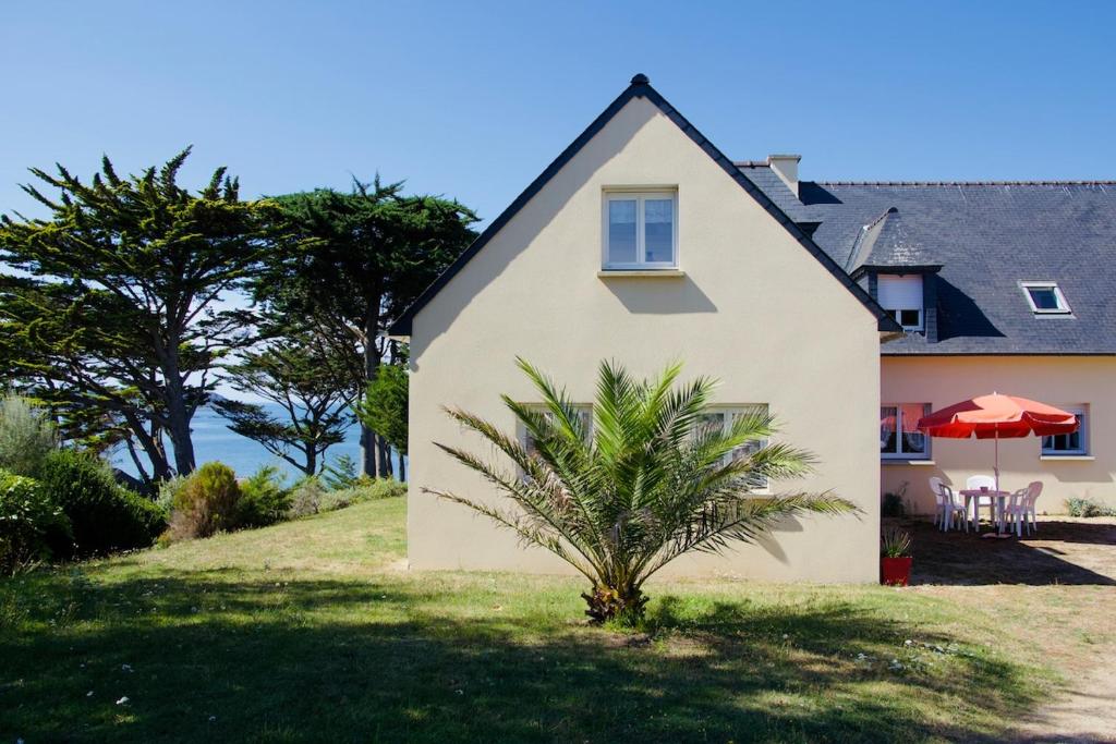 a house with a palm tree in front of it at Family home 7 people, direct beach, sea view in Locquirec