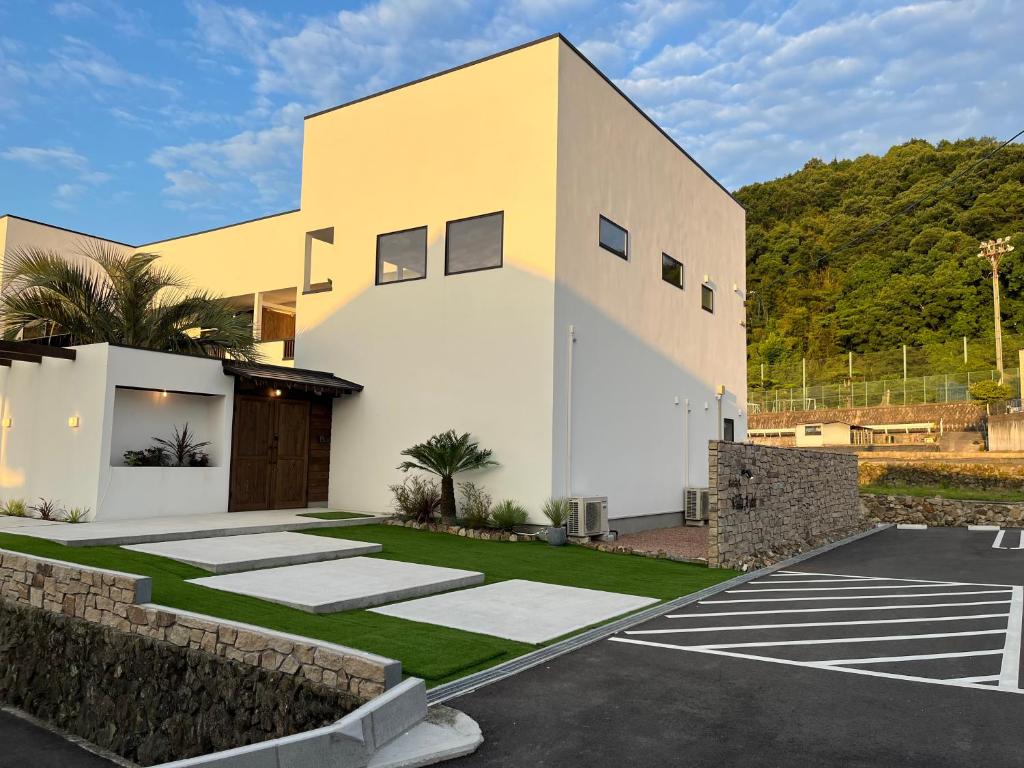 a white building with a parking lot at Onomichi Villa Ayah in Onomichi