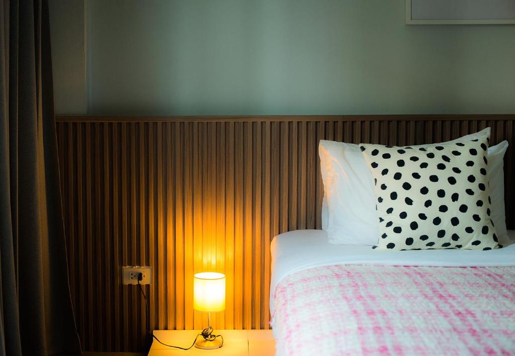 a bed with a black and white pillow and a lamp at Into the town krabi in Krabi town