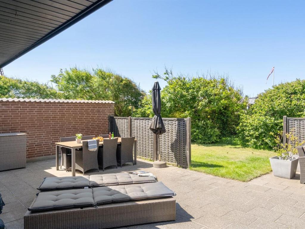 a patio with an umbrella and a table and chairs at Holiday Home Gudlaug - 400m from the sea by Interhome in Blokhus