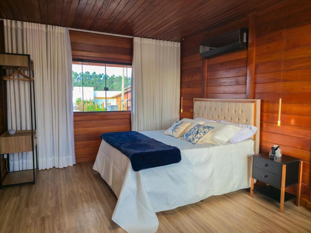Un dormitorio con una cama con paredes de madera y una ventana en Gran Chalé, en Santa Teresa