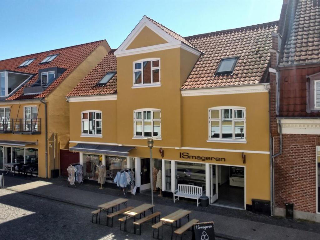un edificio amarillo con bancos delante en Apartment Zlatka - 250m from the sea by Interhome, en Skagen