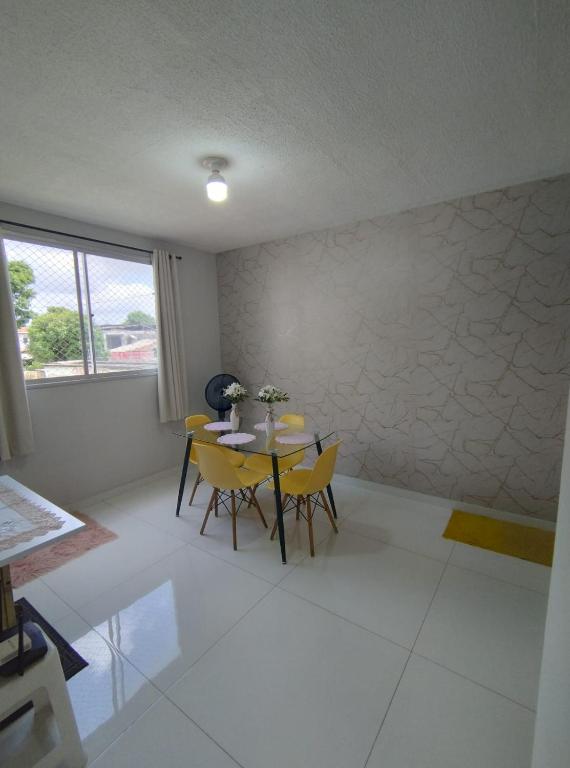 a dining room with a table and yellow chairs at Apartamento in Ananindeua