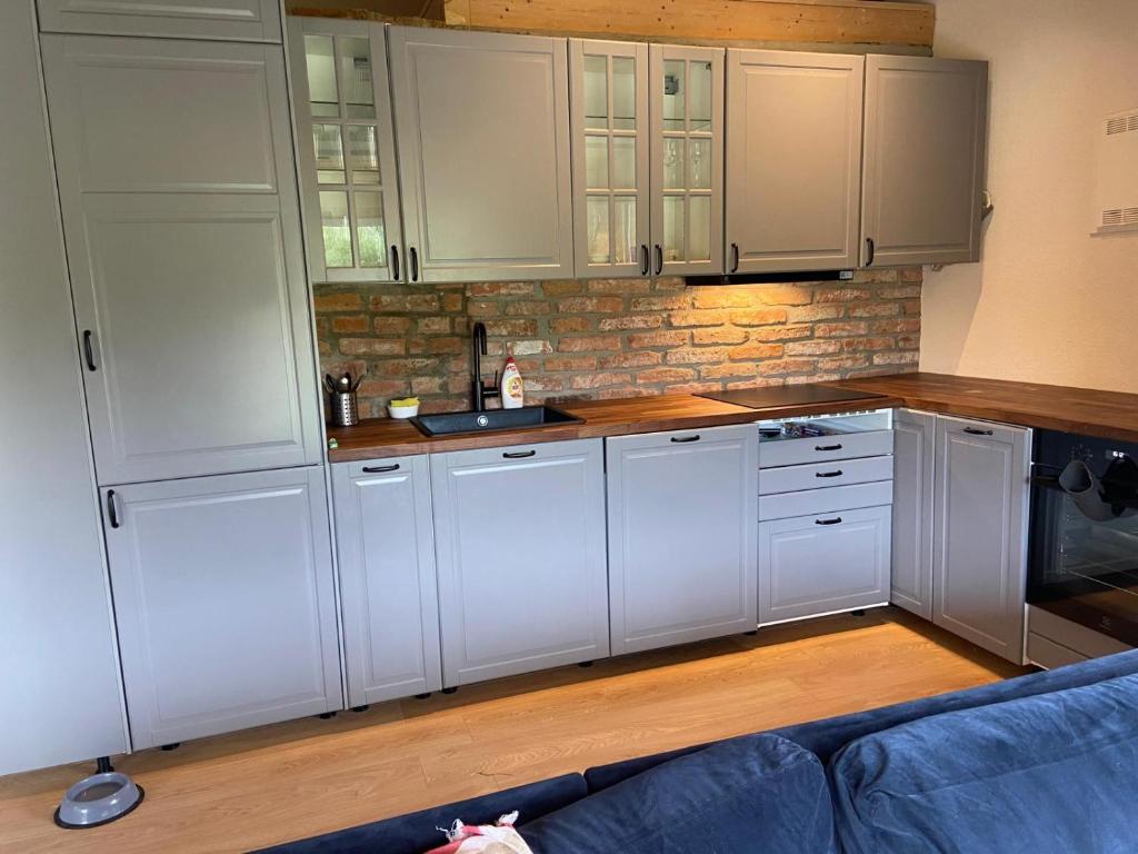 a kitchen with white cabinets and a blue couch at The Trail's Head in Tohanu Nou