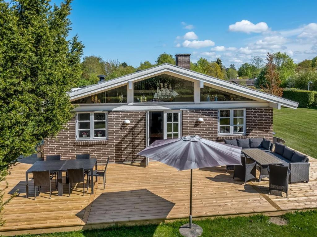 een buitenterras met tafels, stoelen en een parasol bij Holiday Home Melle - 350m from the sea by Interhome in Dronningmølle
