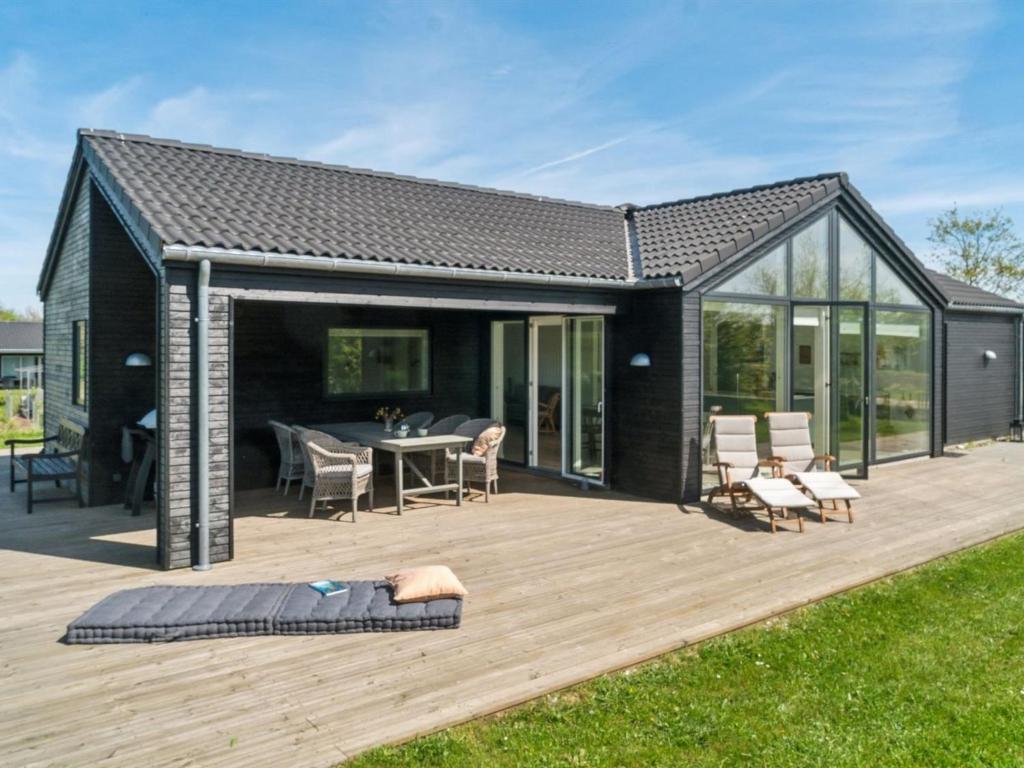 a black house with a deck with a table and chairs at Holiday Home Gregor - 300m from the sea by Interhome in Hørve