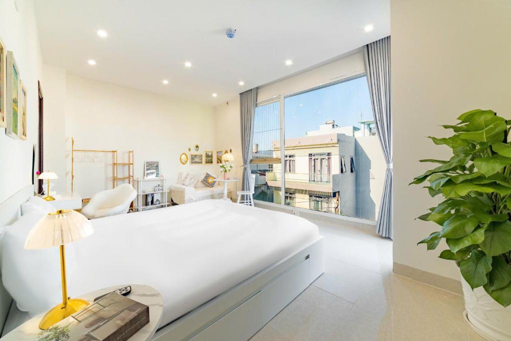 Un dormitorio con una gran cama blanca y una gran ventana. en Danang's house, en Da Nang