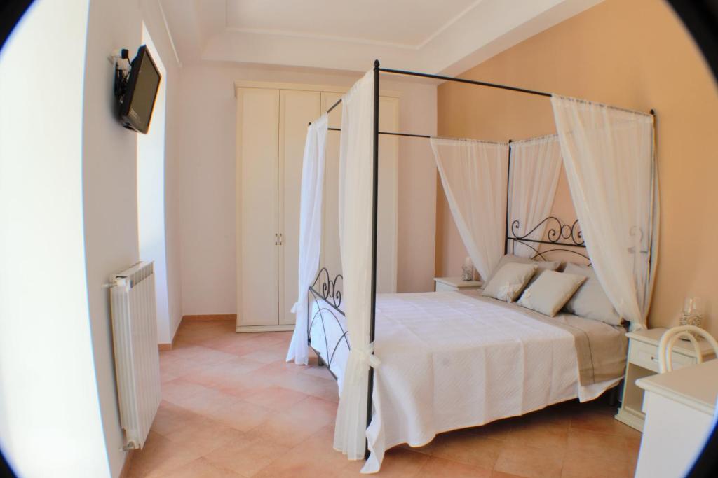 1 dormitorio con cama con dosel, sábanas y almohadas blancas en Montammare Casa Di Charme, en Tramonti