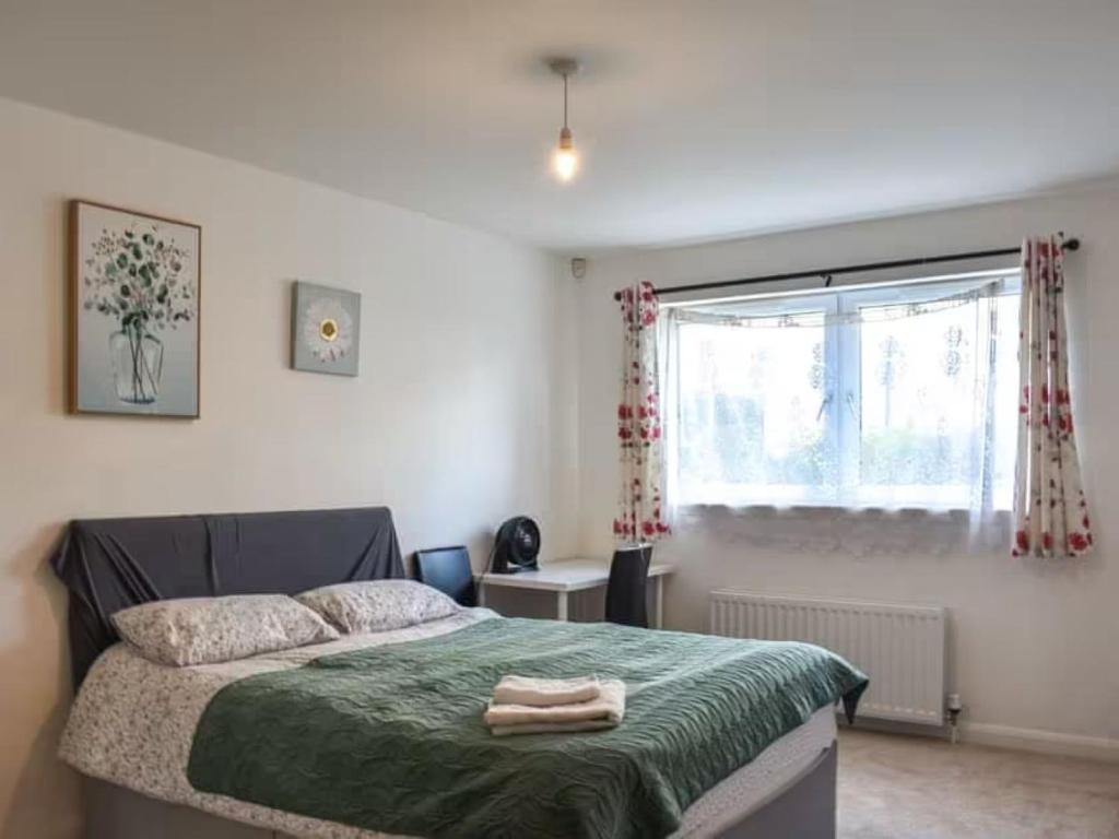 a bedroom with a bed with a green blanket and a window at Spacious 2-Bedroom Ground Floor Flat with 2 Double Beds, Sleeps 4 in Central Aberdeen in Aberdeen