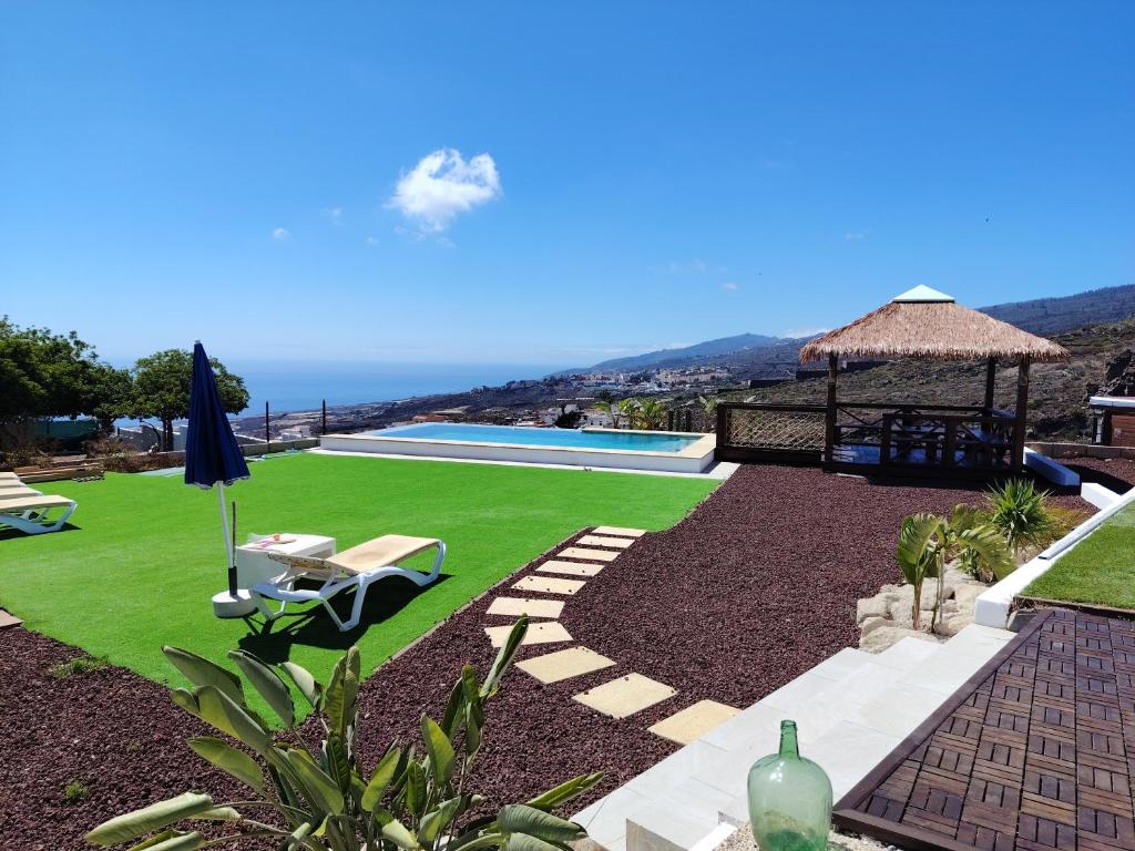 a backyard with a lawn and a swimming pool at Preciosa cabaña in Guía de Isora
