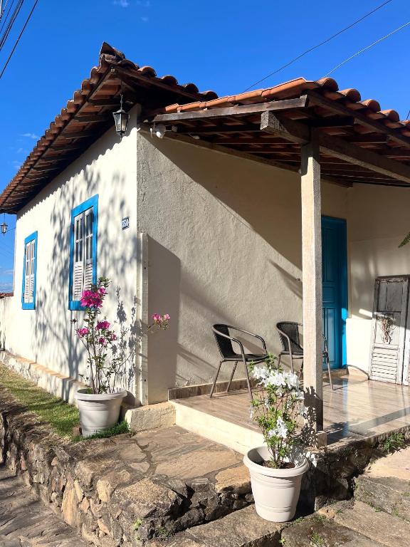 a house with two chairs and a porch with flowers at Casa Donna Flor 2 Quartos Completa Centrinho com Garagem Coberta in Catas Altas