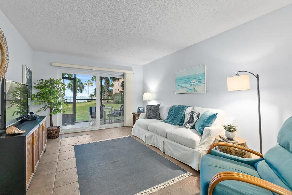Gone Coastal l Ground Floor Condo l Steps to Beach في Anastasia Island: غرفة معيشة مع أريكة وتلفزيون