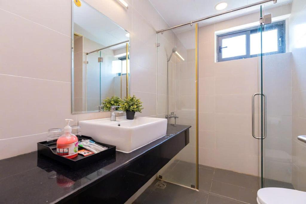une salle de bain avec un lavabo et une douche en verre dans l'établissement Aria Vũng Tàu - Blue Sapphire Resort Căn Hộ, Biệt Thự Nghỉ Dưỡng Cách Biển 50m, à Xã Thắng Nhứt
