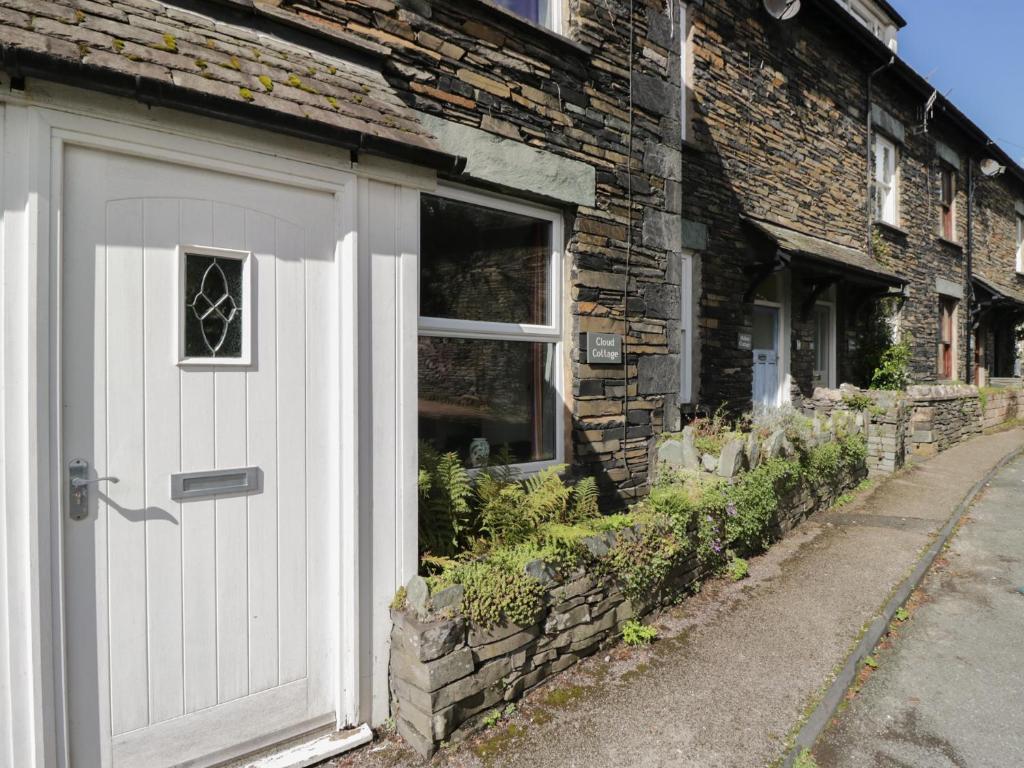 eine weiße Tür an der Seite eines Backsteingebäudes in der Unterkunft Cloud Cottage in Ambleside