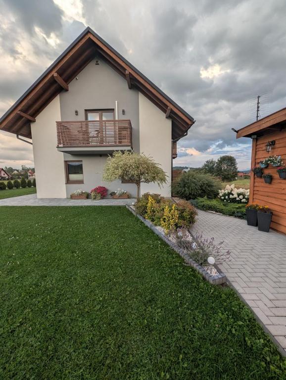 a house with a balcony and a grass yard at Apartament Przy Potoku in Zubrzyca Górna