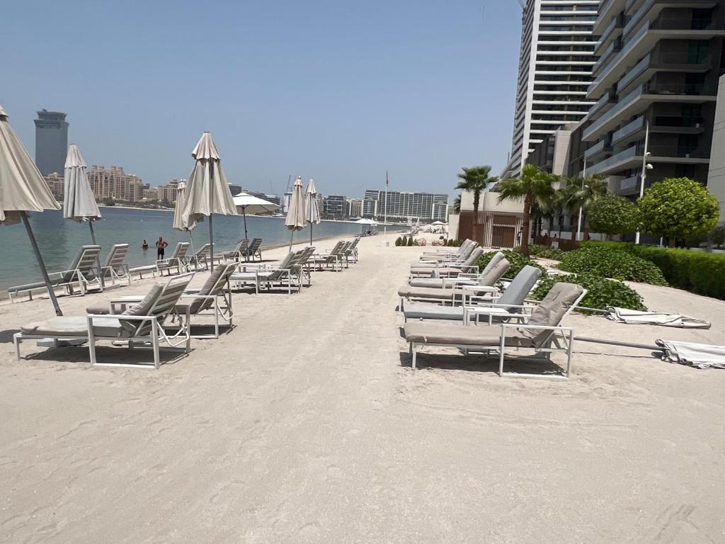 eine Reihe von Liegestühlen und Sonnenschirmen an einem Strand in der Unterkunft Luxury 2 Bedroom Apartment - Private Beach - Emaar Beach Vista in Dubai