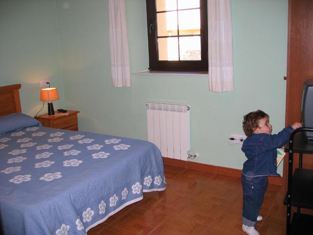 un niño pequeño jugando con un videojuego en un dormitorio en Hotel Fitu en Colunga