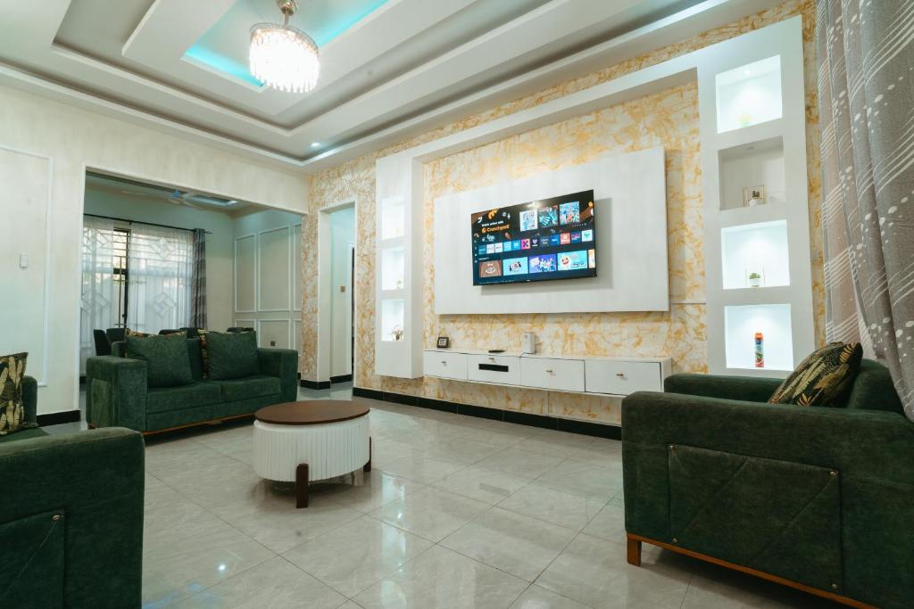 ein Wohnzimmer mit Sofas und einem TV an der Wand in der Unterkunft Entire house - all rooms AC - close to beach - washingmachine in Daressalam
